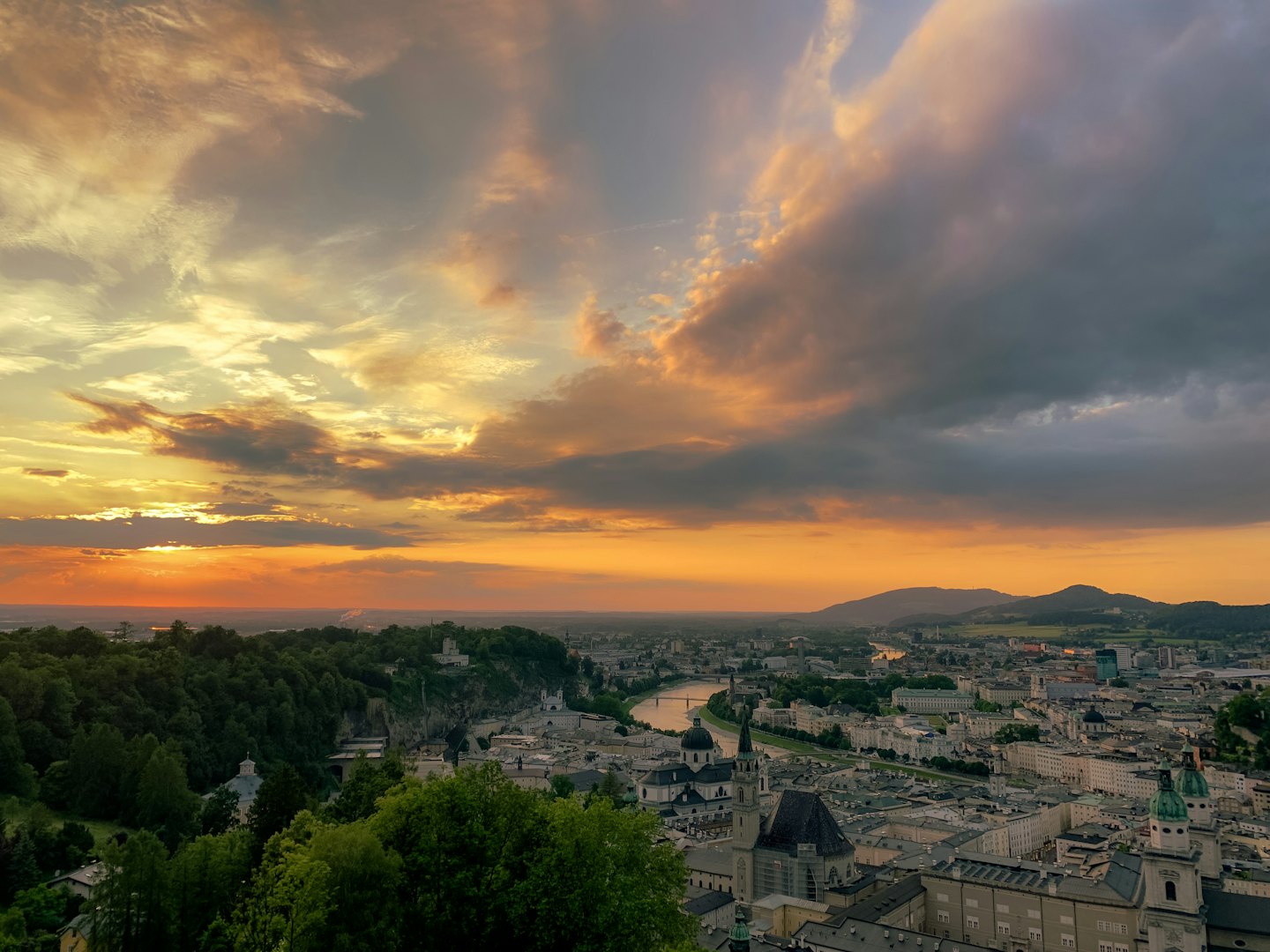Eine historische europäische Stadt an einem Fluss in der Nähe von bewaldeten Hügeln.
