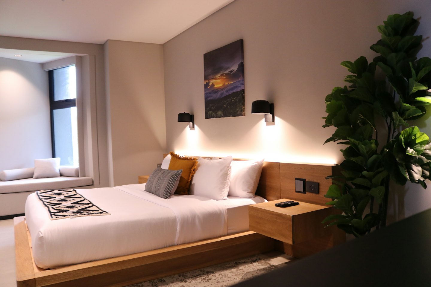 Modernes Hotelzimmer mit weißer Bettwäsche und einer grünen Pflanze.