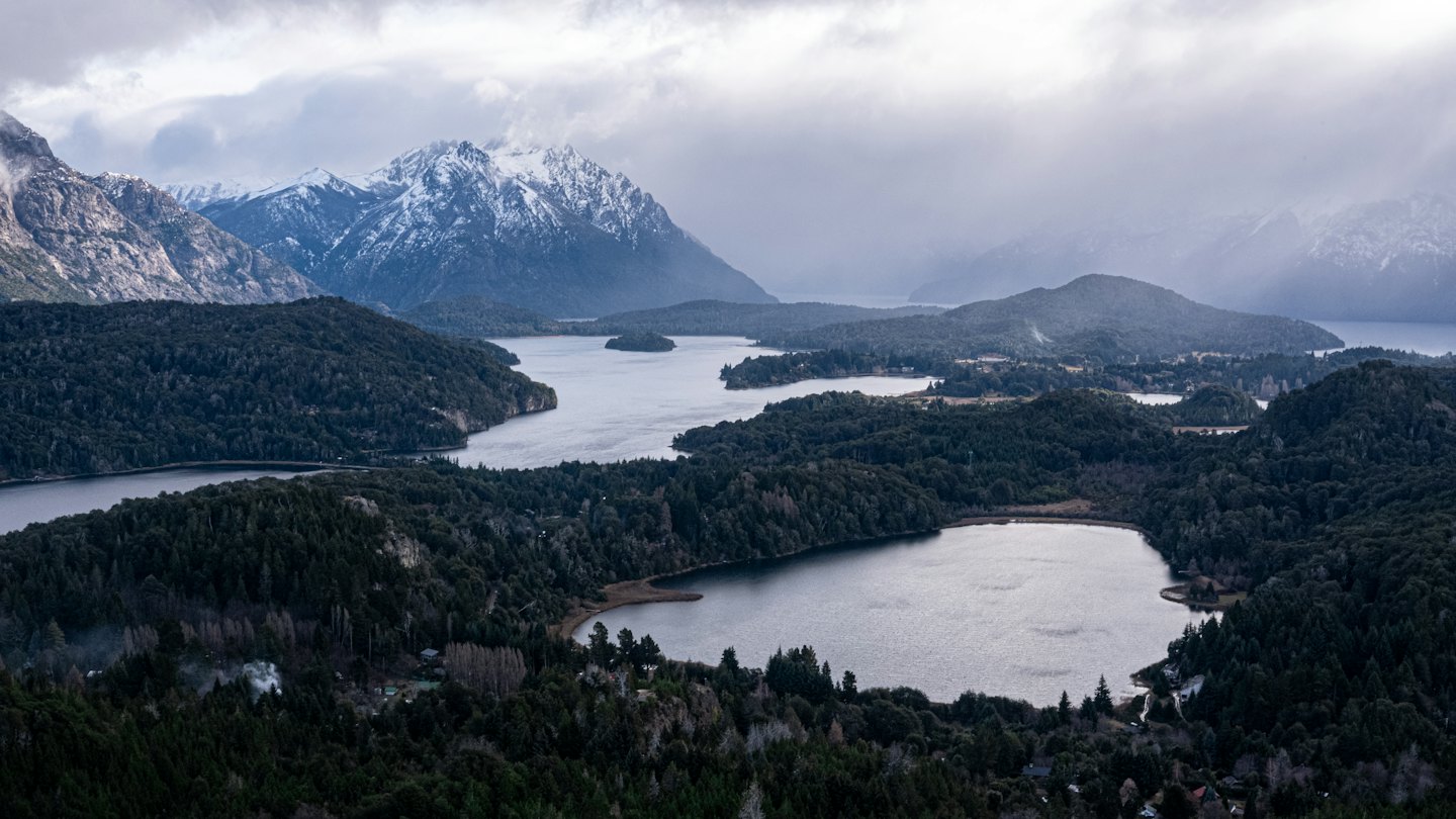 Verbundene Seen, umgeben von Nadelwäldern und schneebedeckten Bergen.