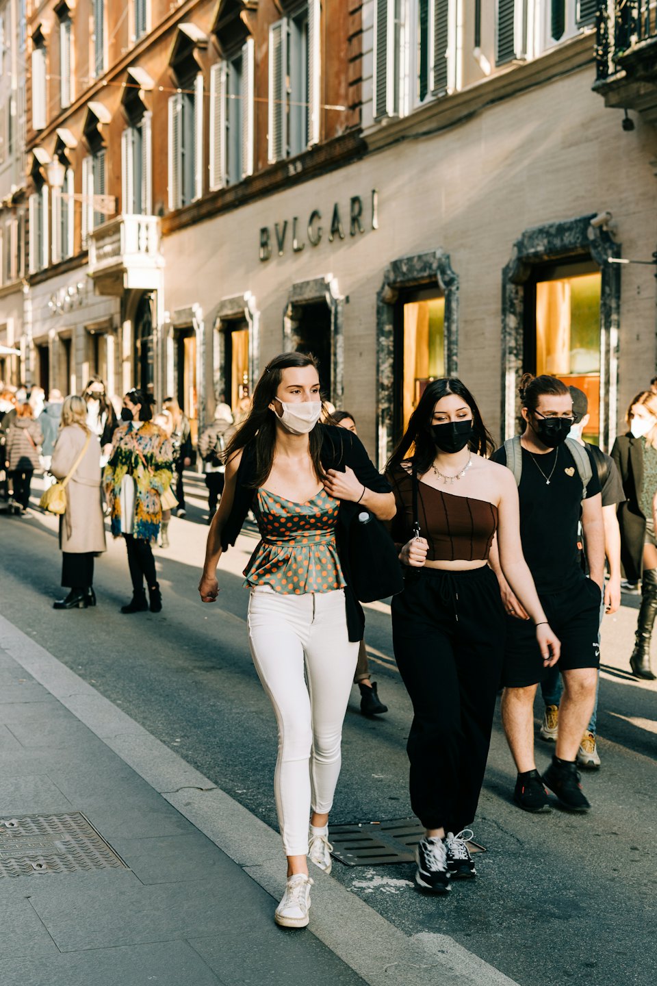 Fußgänger mit Masken gehen an einem Luxusgeschäft von Bvlgari vorbei.