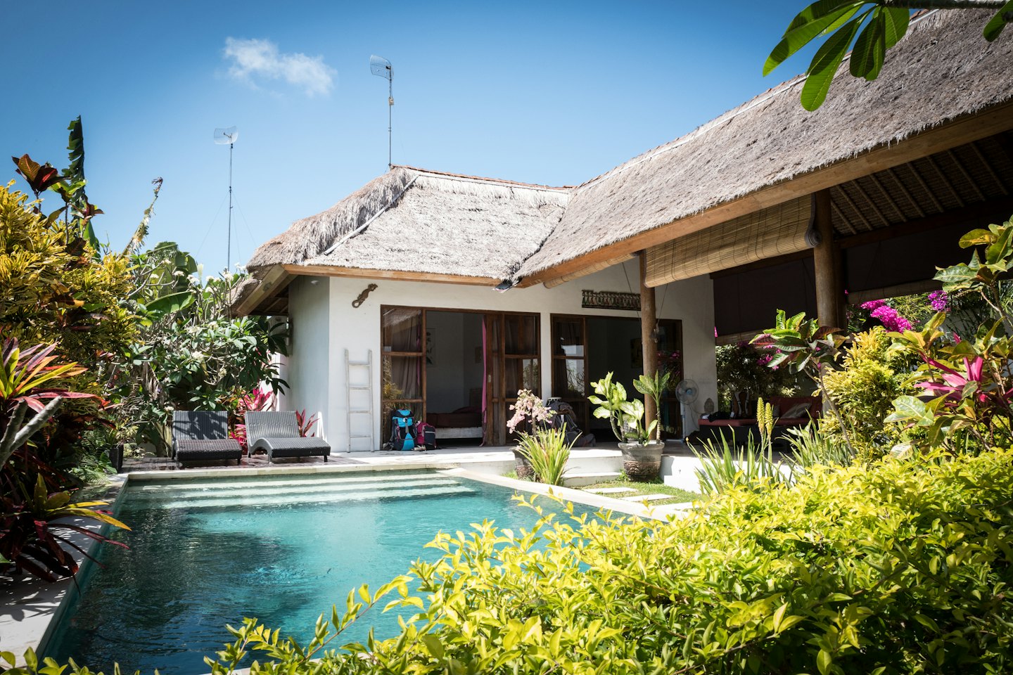 Tropische Villa mit privatem Pool unter blauem Himmel.